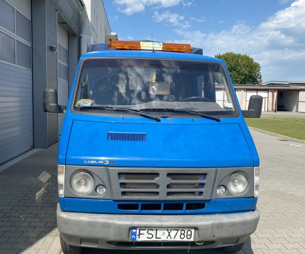 Samochód ciężarowo -osobowy marki lublin stojący przed wjazdem do garażu, widoczny przód kabiny.