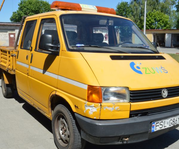 Samochód marki Volkswagen Transporter w kolorze żółtym na tle budynku Zakładu Usług Wodno-Ściekowych w Słubicach.