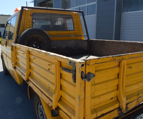Samochód marki Volkswagen Transporter w kolorze żółtym na tle budynku Zakładu Usług Wodno-Ściekowych w Słubicach- widok paki.