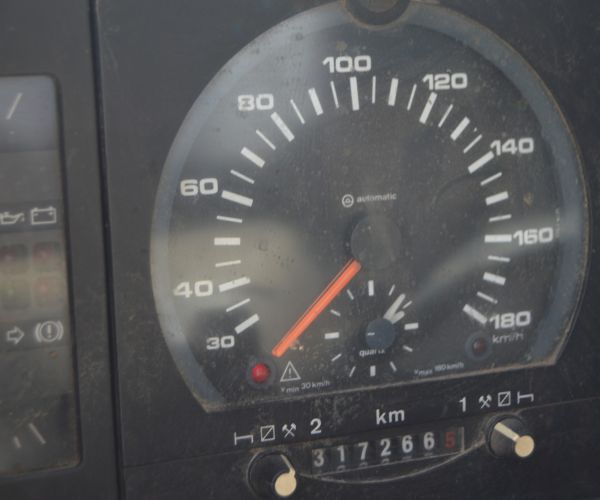Samochód marki Volkswagen Transporter w kolorze żółtym na tle budynku Zakładu Usług Wodno-Ściekowych w Słubicach- widok licznika.